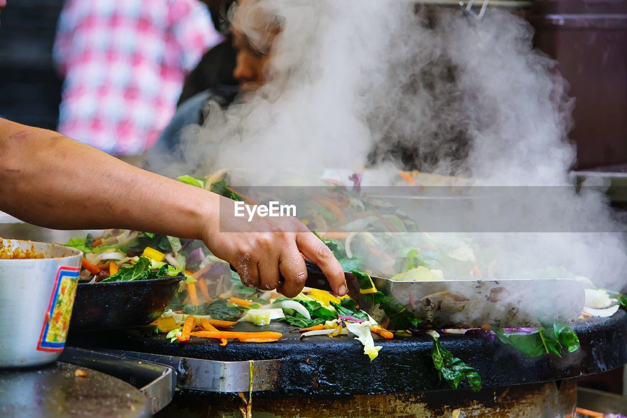 Cropped image of person preparing vegetables at market stall