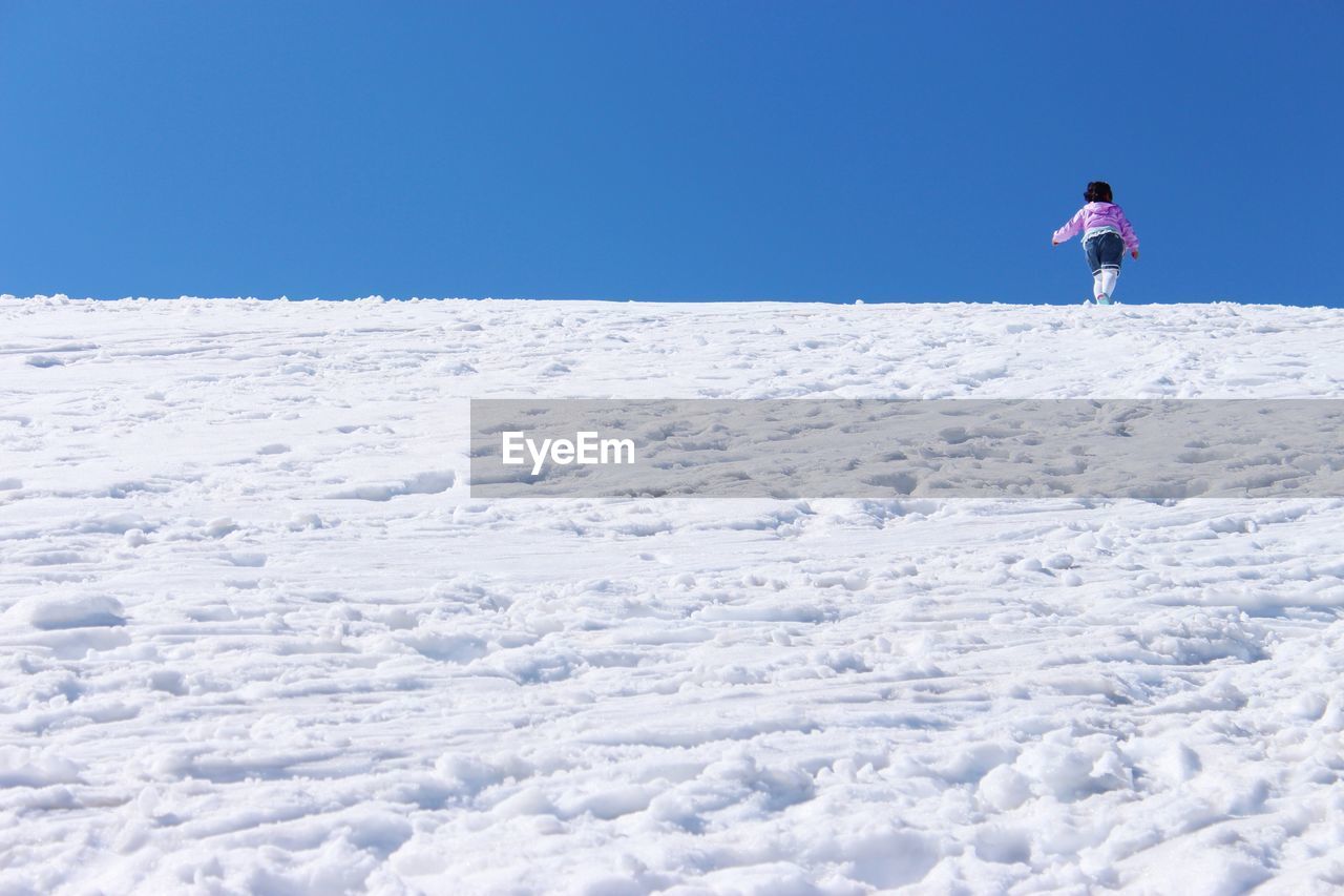 FULL LENGTH OF MAN STANDING ON SNOW AGAINST CLEAR SKY