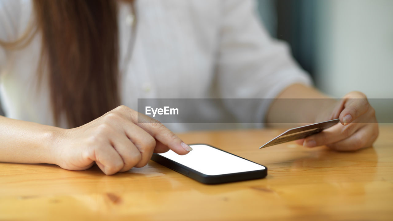 MIDSECTION OF WOMAN USING MOBILE PHONE