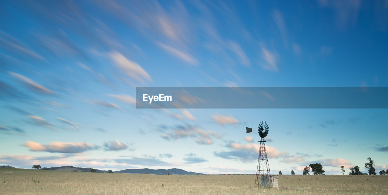 Windmill on grass field against sky