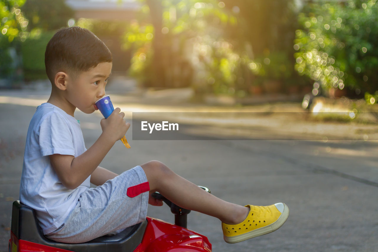 Boy eating while sitting on toy car