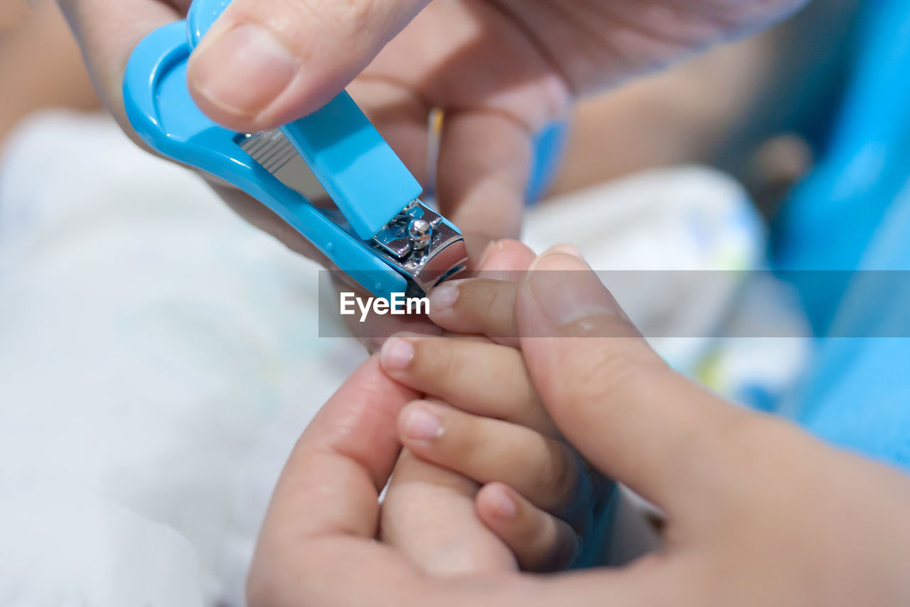 Close-up of mother cutting nails of baby at home