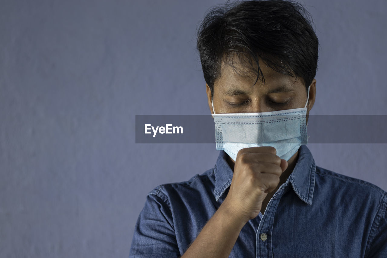 Health problem and people concept - unhealthy indian man coughing with nose mask on