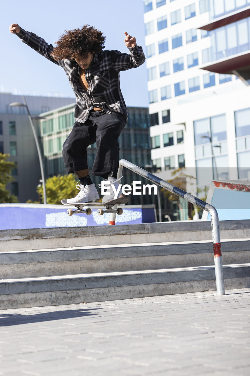 Sportsperson jumping while skateboarding at skateboard park