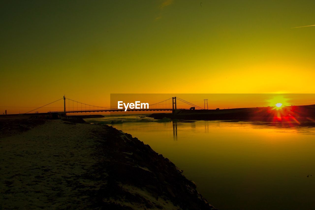 SCENIC VIEW OF SUSPENSION BRIDGE OVER SEA AGAINST SKY DURING SUNSET