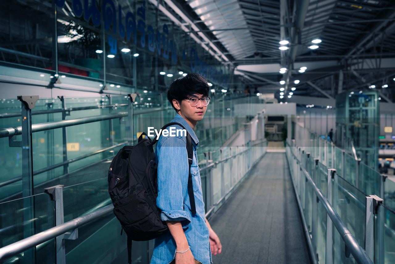 Portrait of young man standing on moving walkway