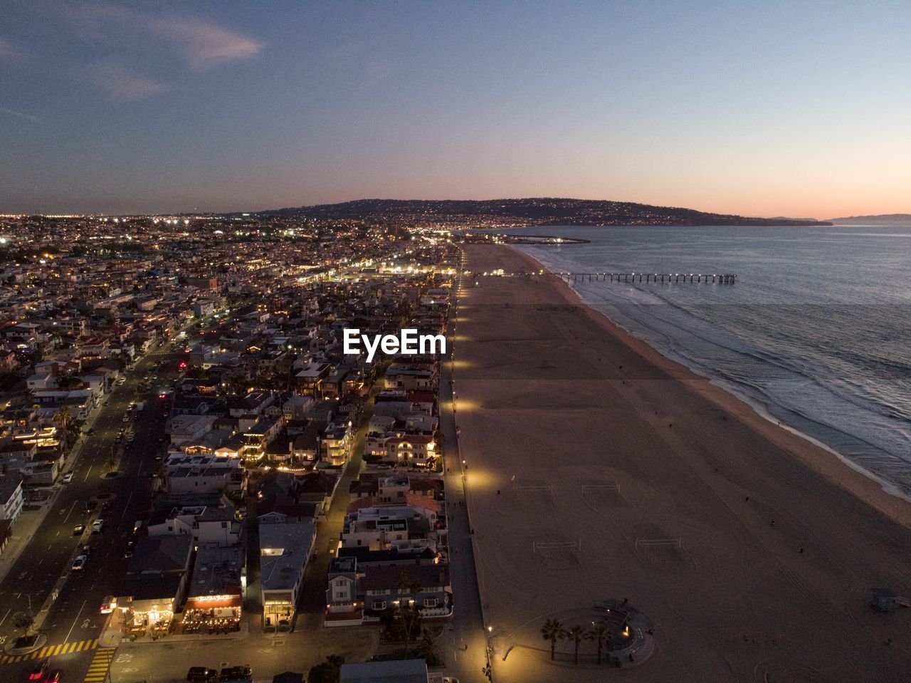 High angle view of illuminated city by sea against sky