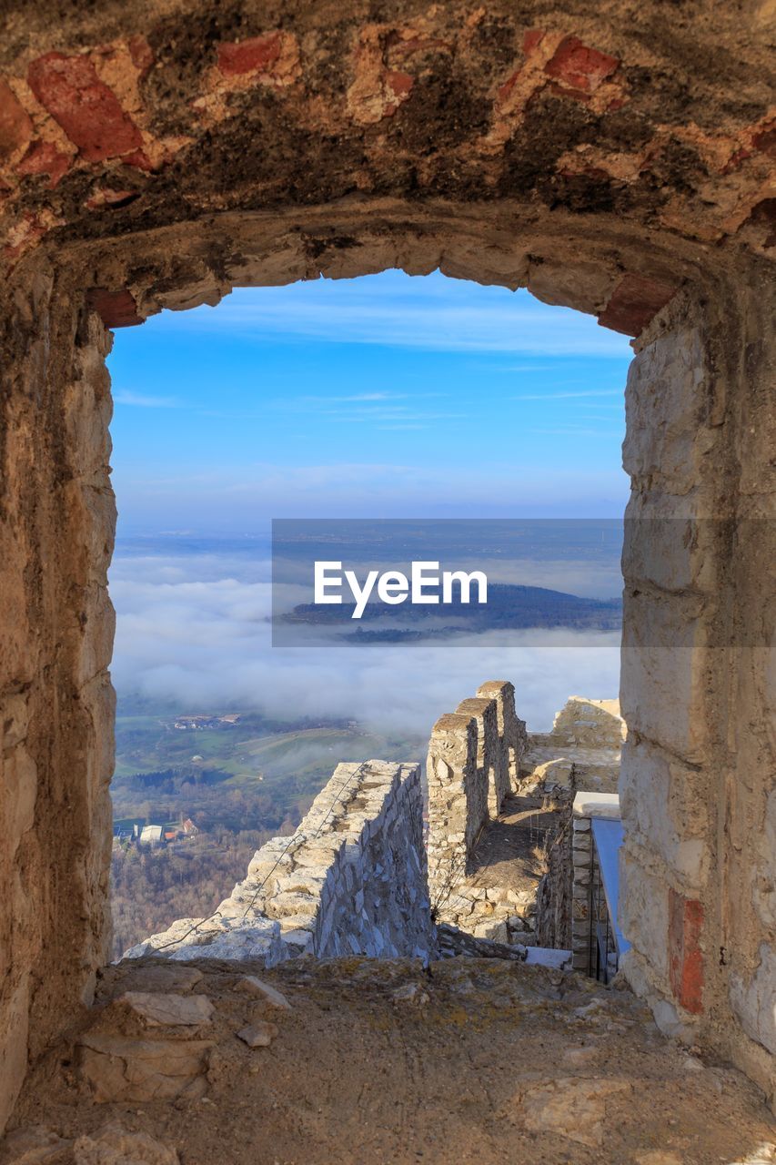 Scenic view of cloudkit landscape against sky seen through arch