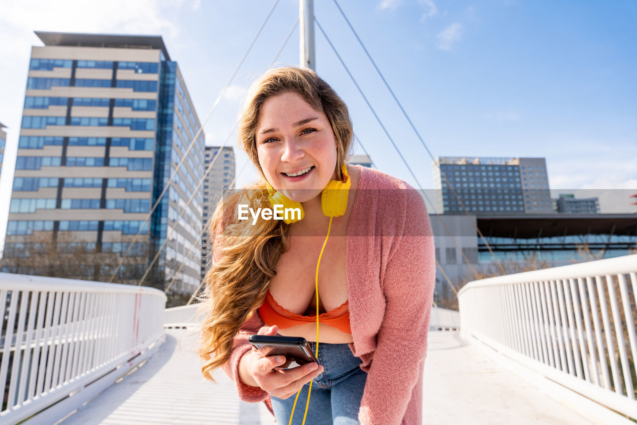 Portrait of young woman photographing in city