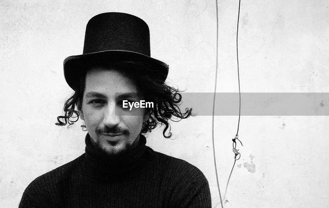 PORTRAIT OF YOUNG MAN WEARING HAT AGAINST WALL