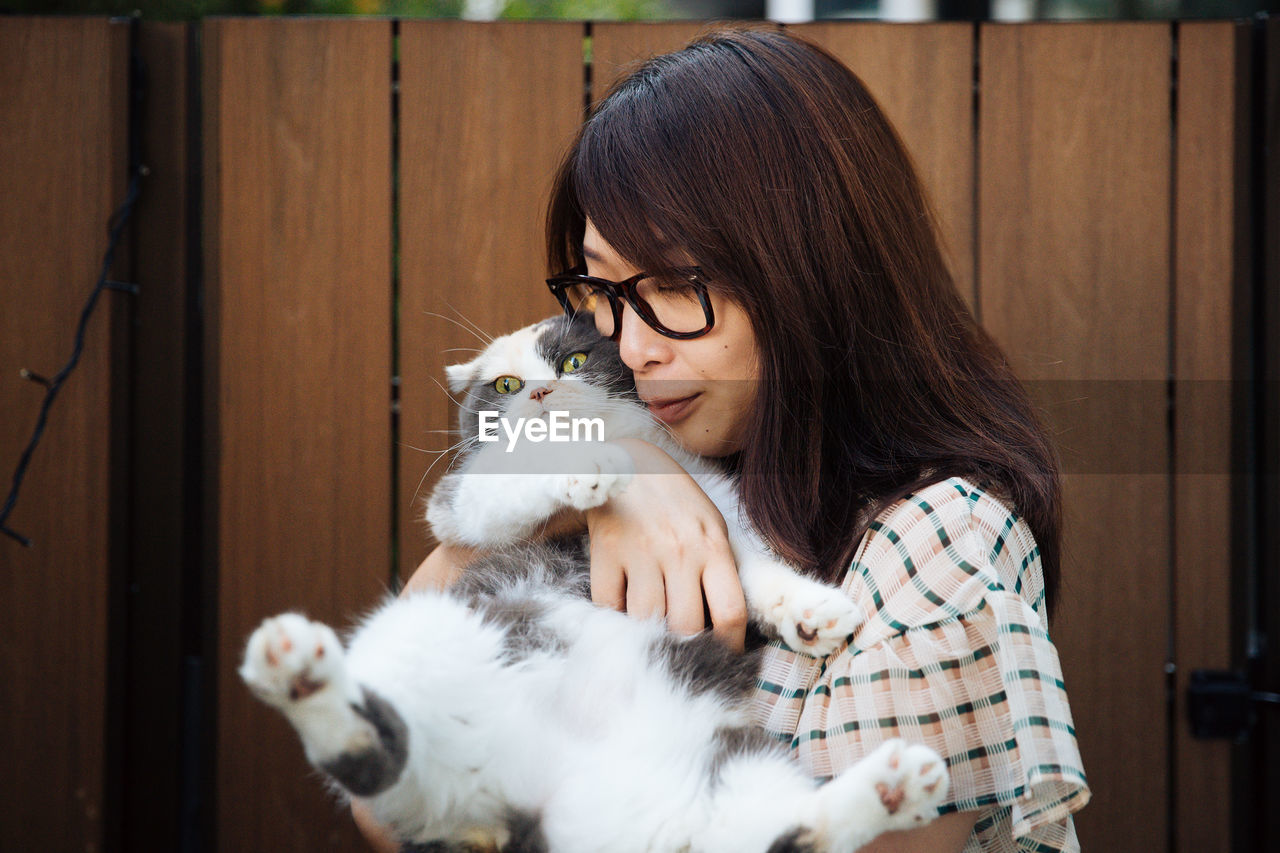 Close-up of woman carrying cat against wall