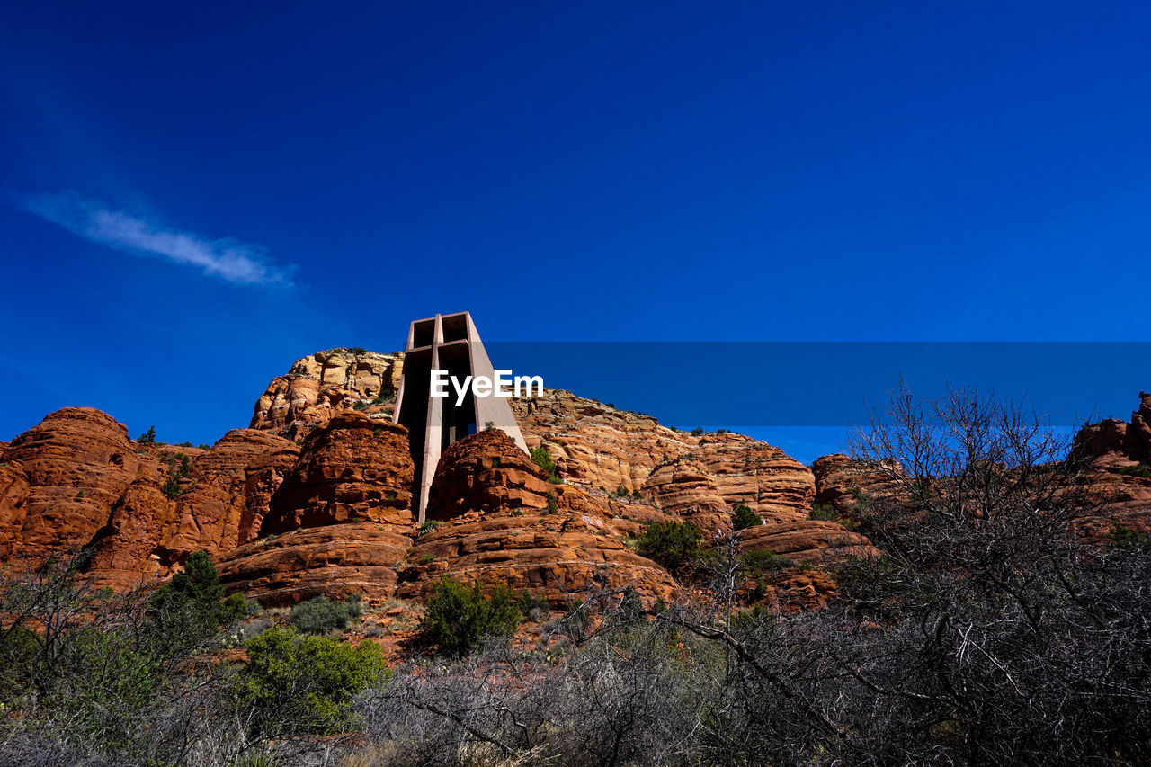 Low angle view of rocks on mountain against blue sky