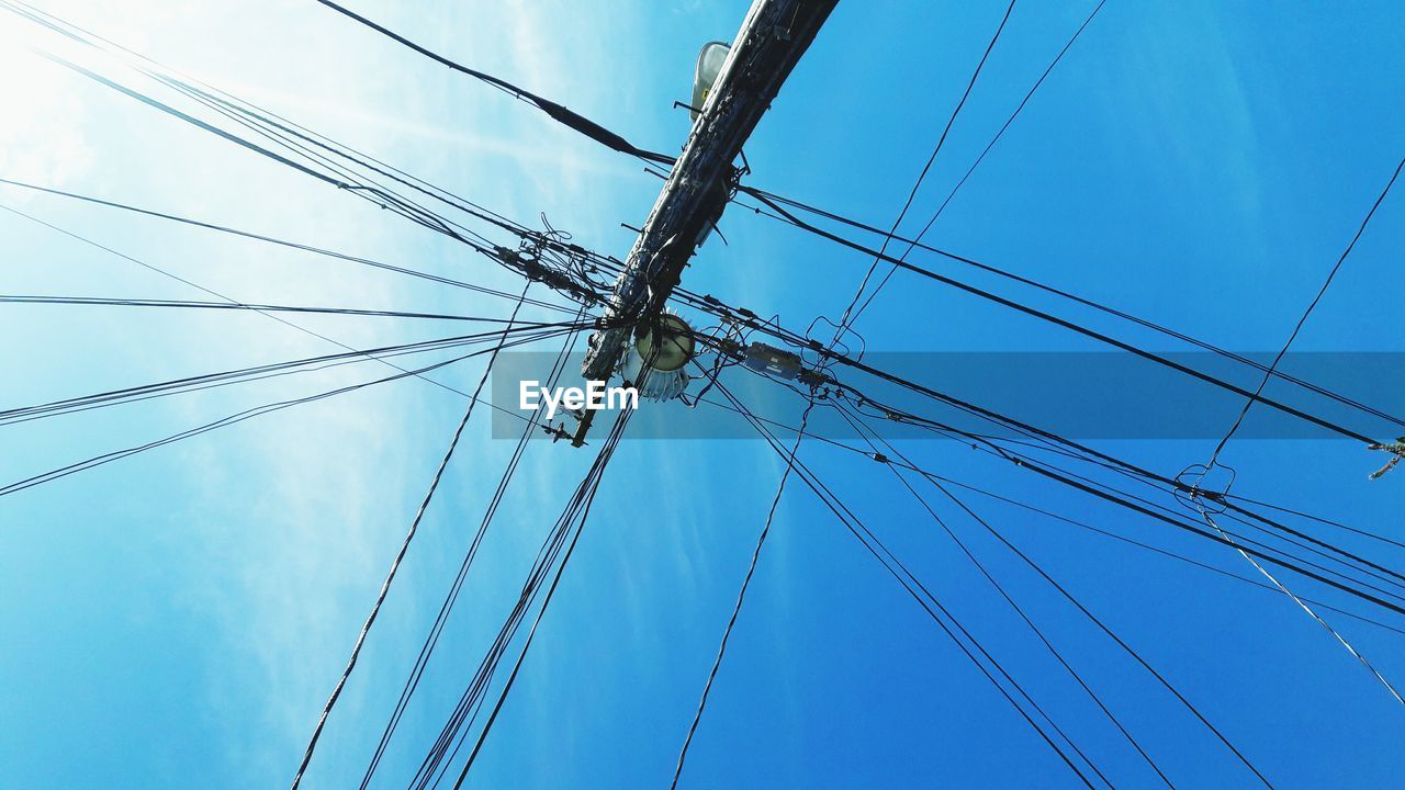 Low angle view of power cables against sky