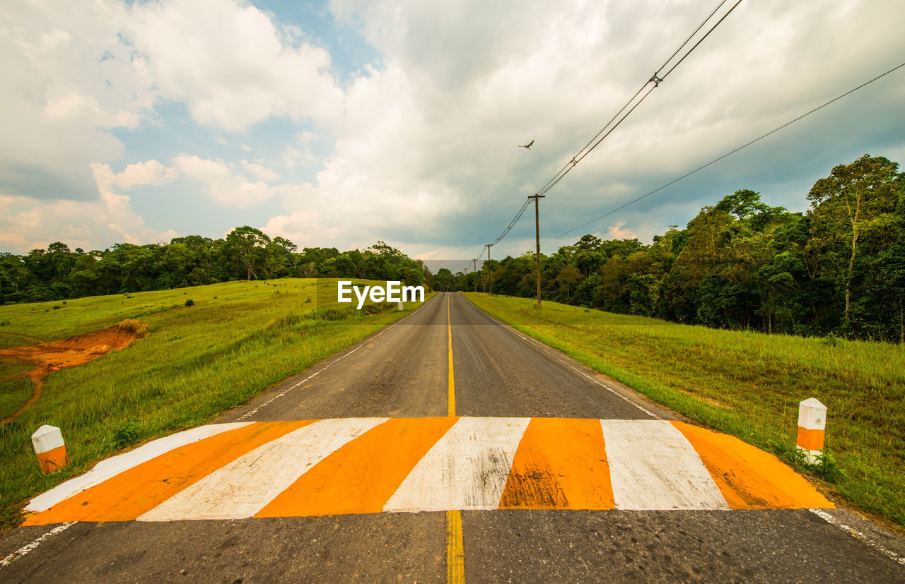 ROAD BY TREES AGAINST SKY