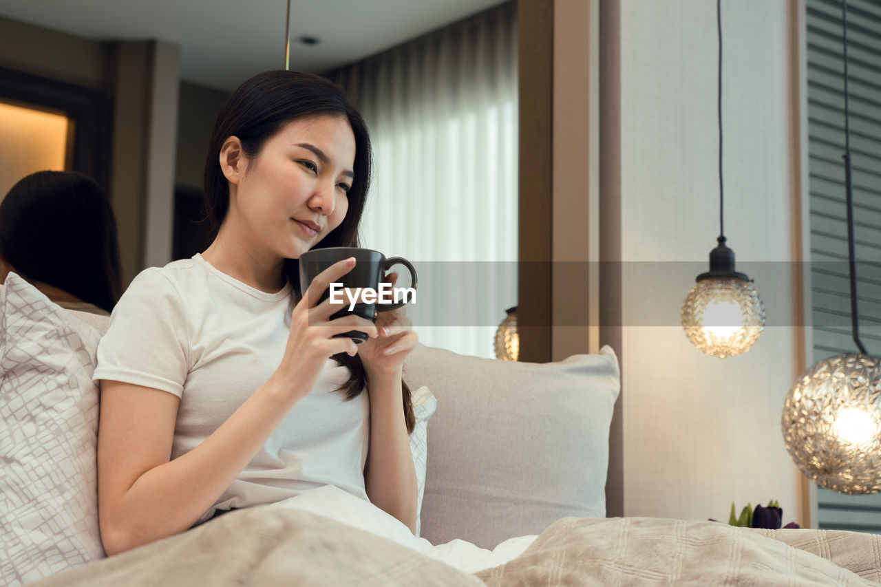 YOUNG WOMAN USING SMART PHONE ON BED