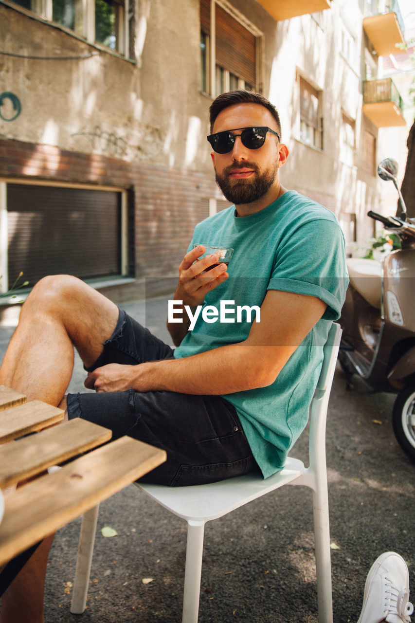 Man drinking coffee while sitting on chair