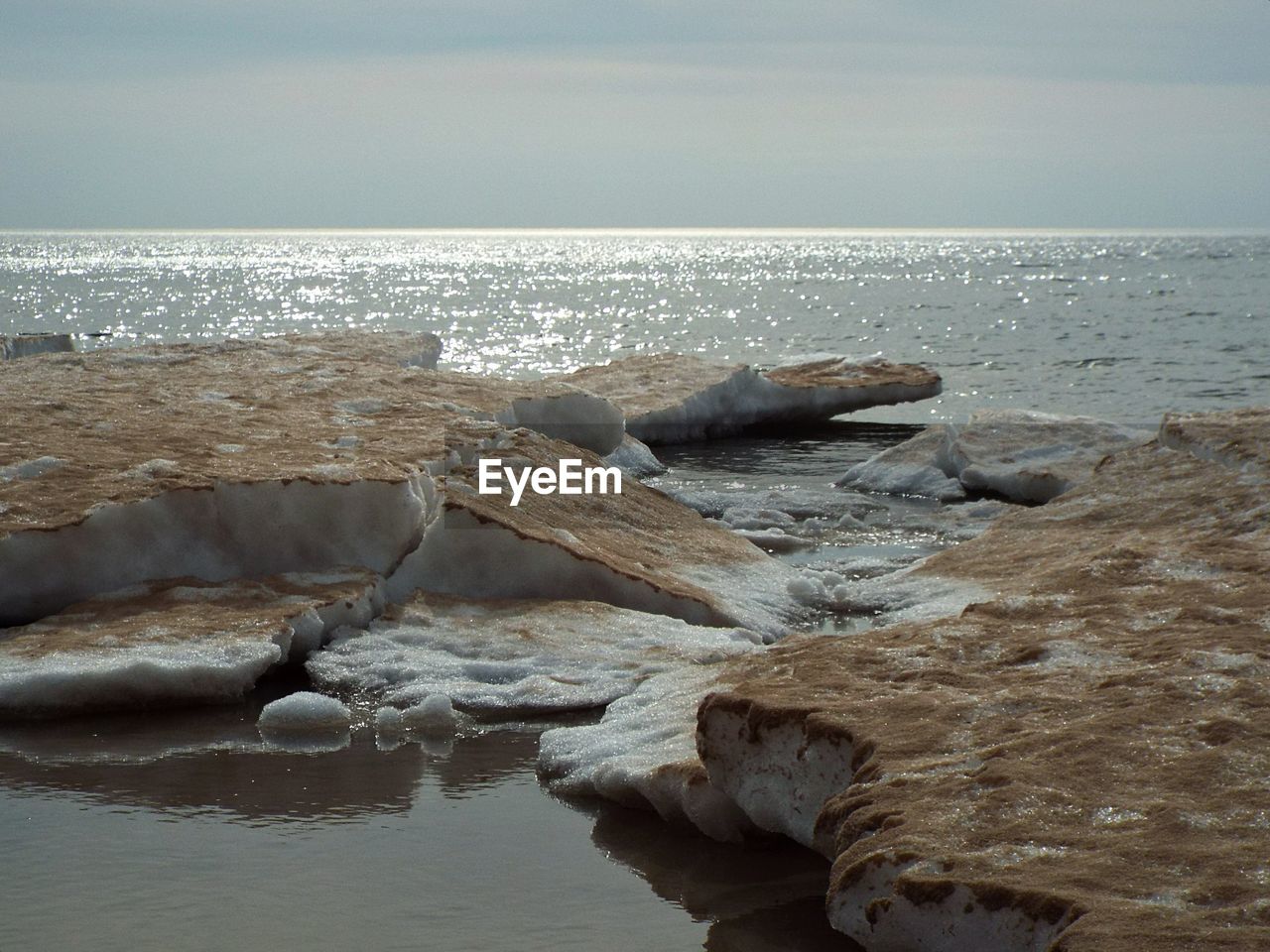 ROCKS AT BEACH AGAINST SKY