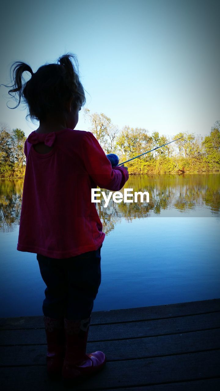 REAR VIEW OF GIRL STANDING ON LAKE