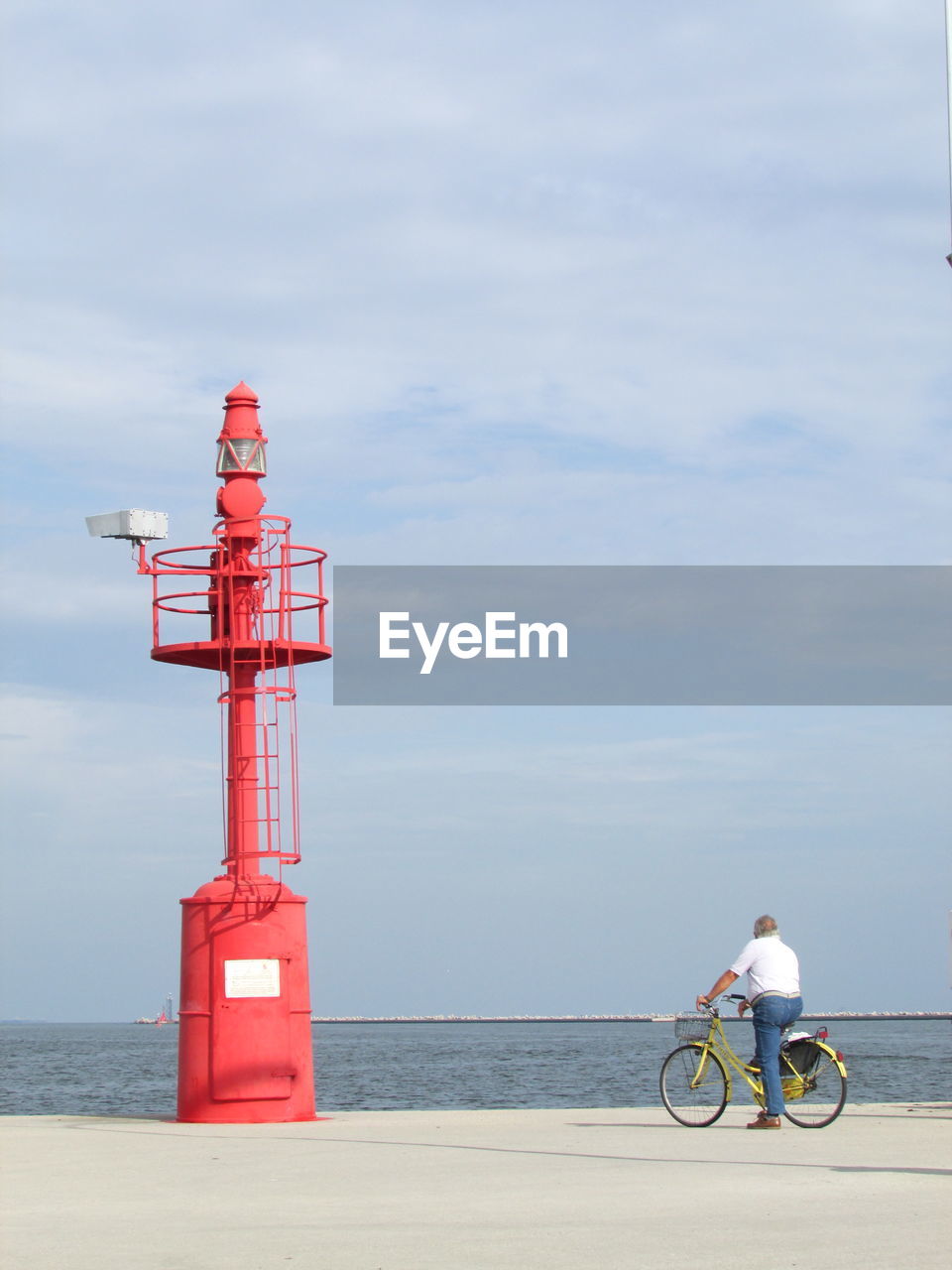 Man and lighthouse by sea against sky