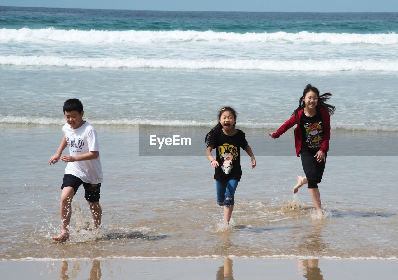 Full length of happy children running on beach