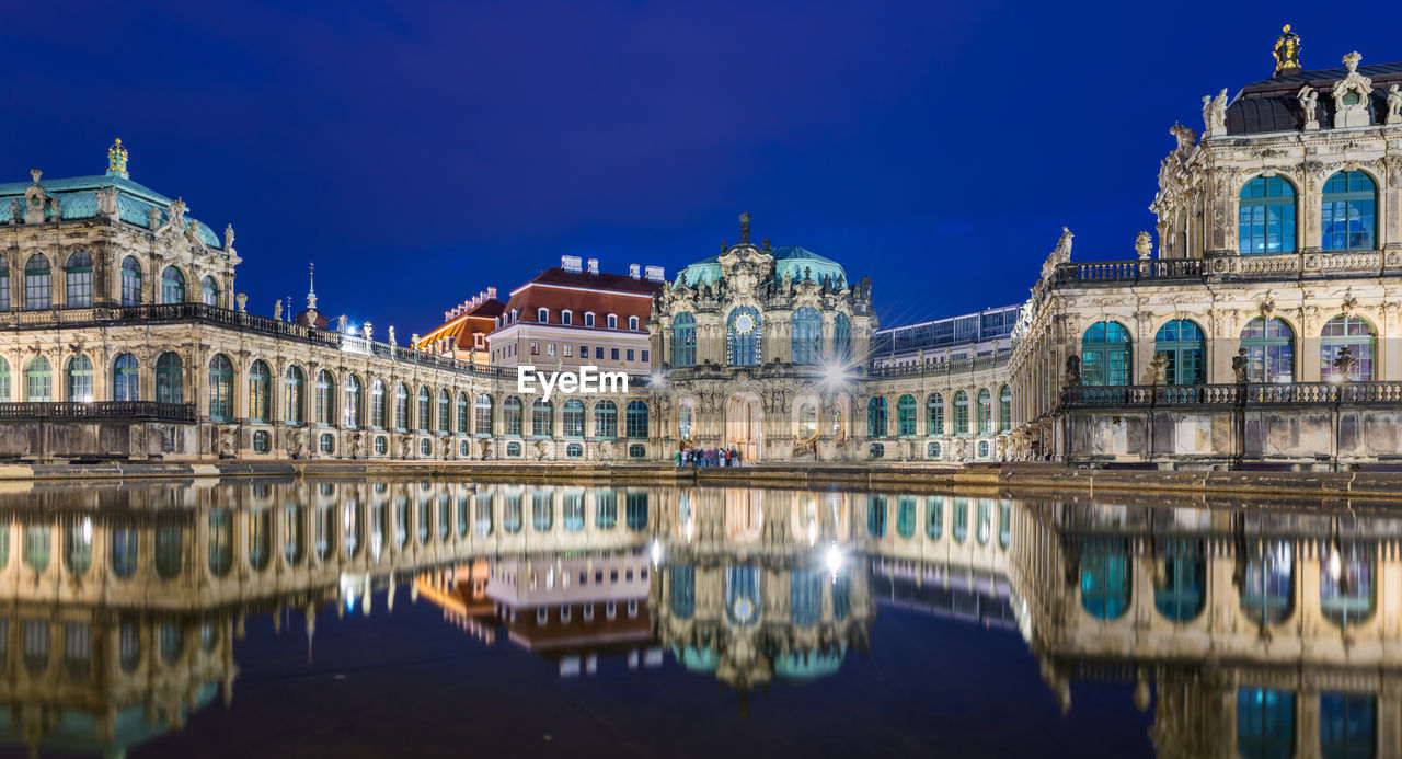 Zwinger museum reflecting on lake against blue sky