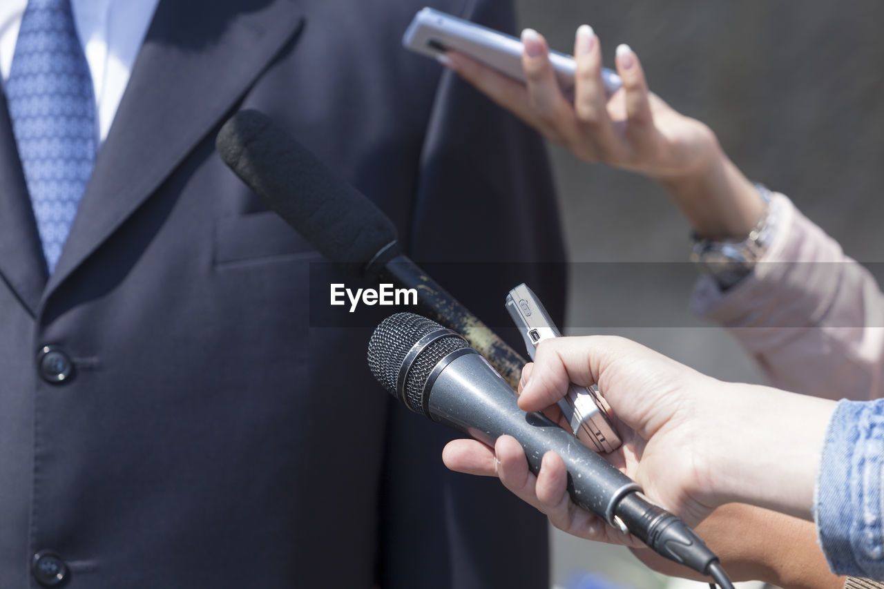 Cropped hand interviewing businessman with microphone