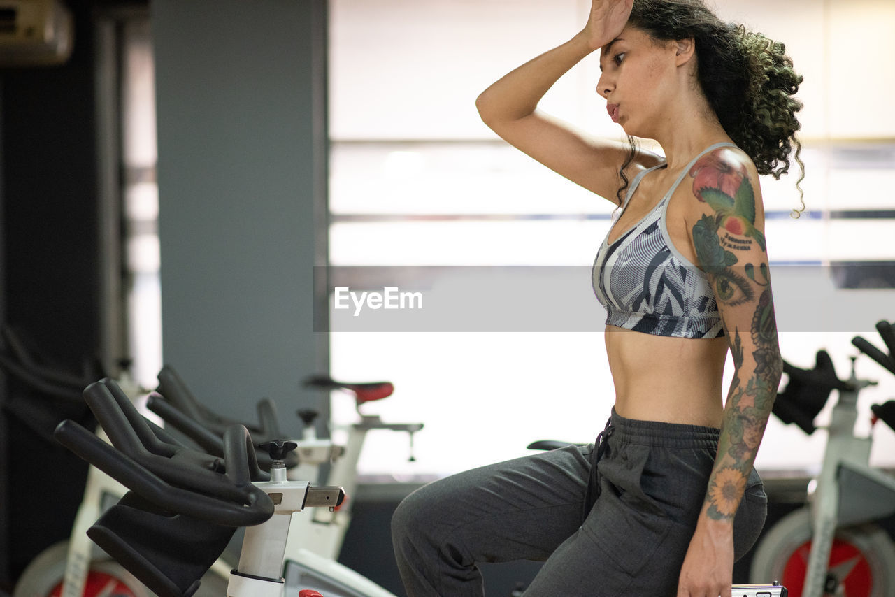 Young woman resting on bicycle at the gym