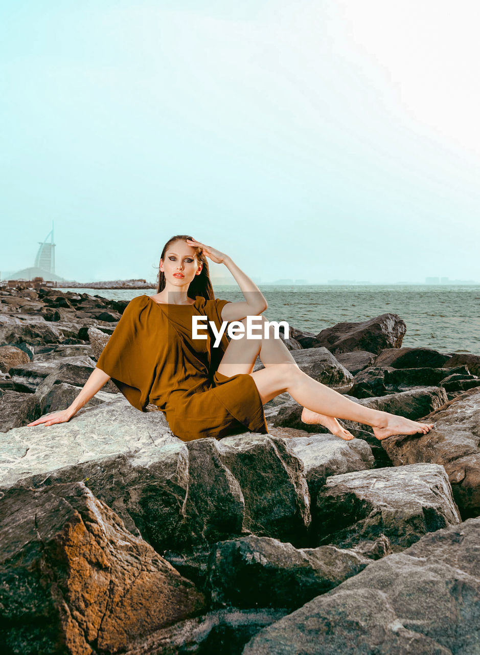 Young woman sitting on rock at beach