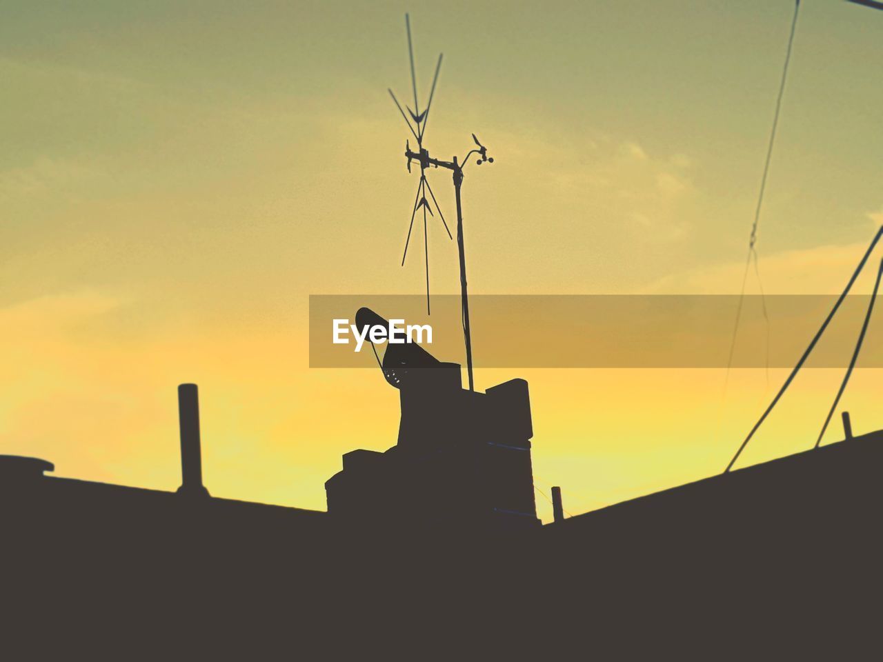 LOW ANGLE VIEW OF SILHOUETTE ANTENNA ON ROOF AGAINST SKY