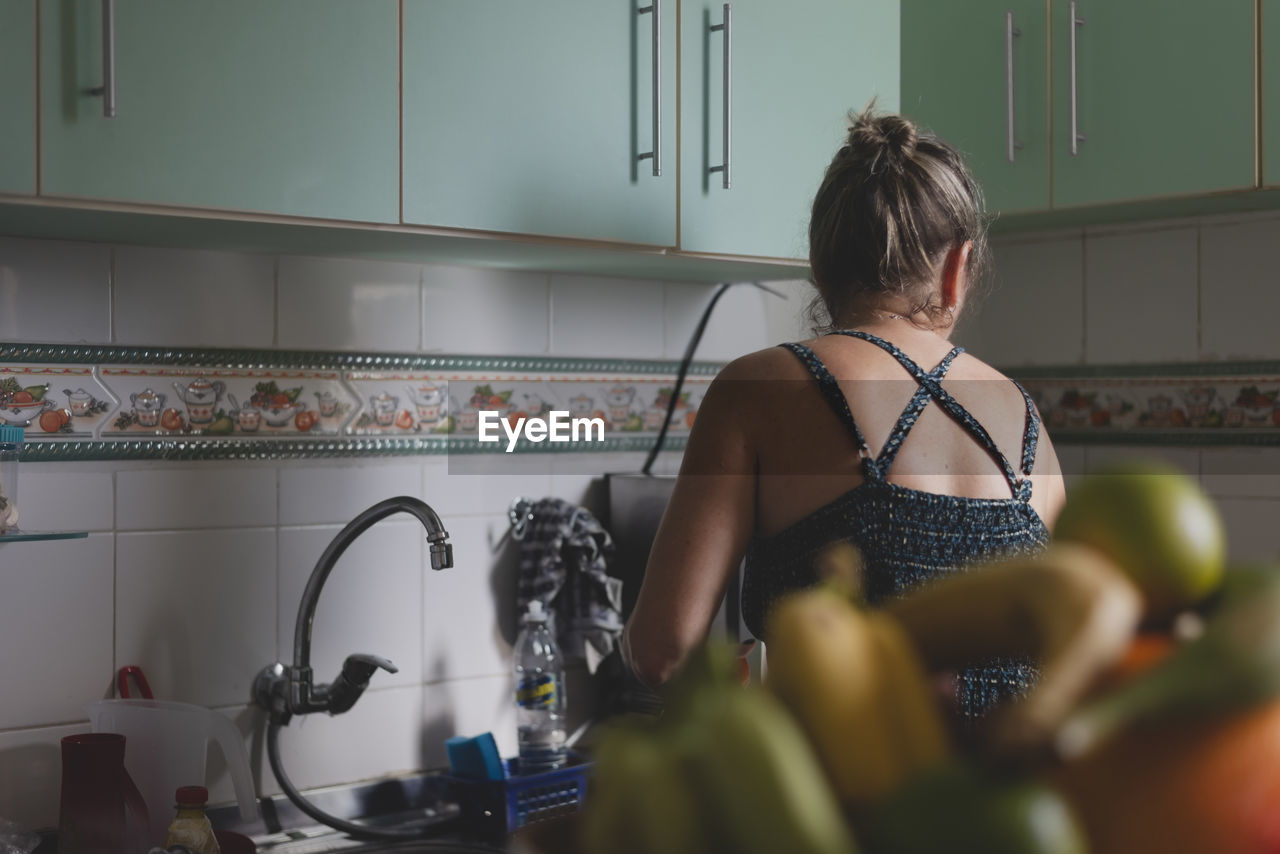 Caucasian woman with her back to her cooking in the kitchen. 