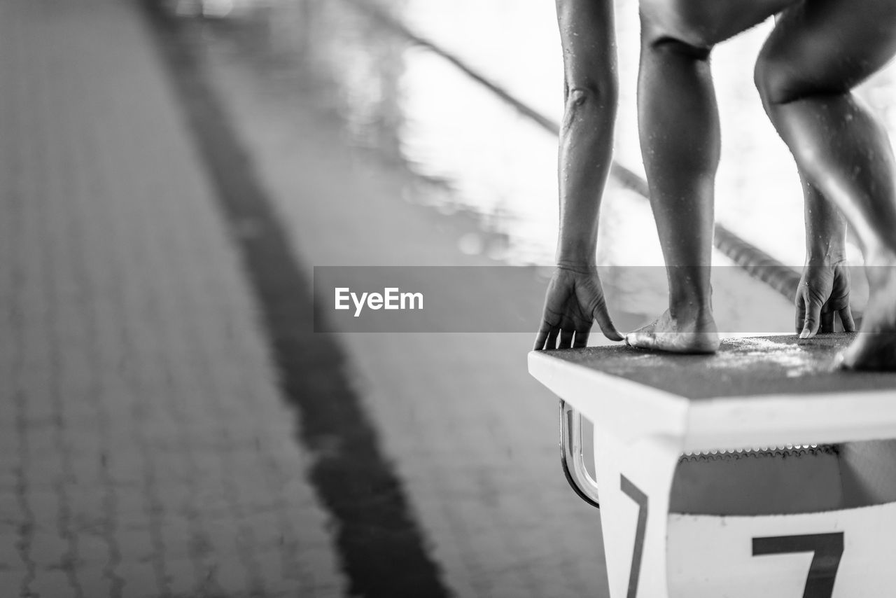 Low section of woman standing on block in swimming pool