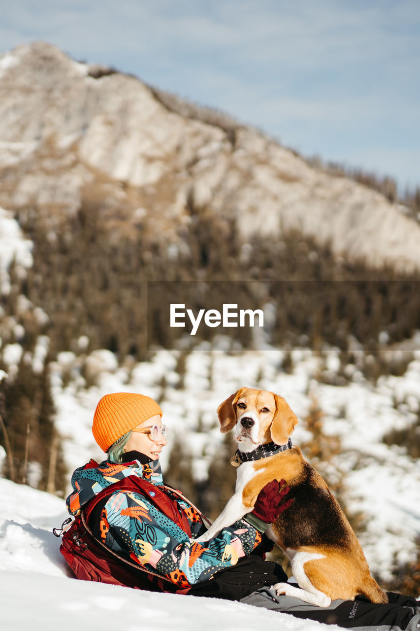 Dog and girl sitting on snow covered mountain