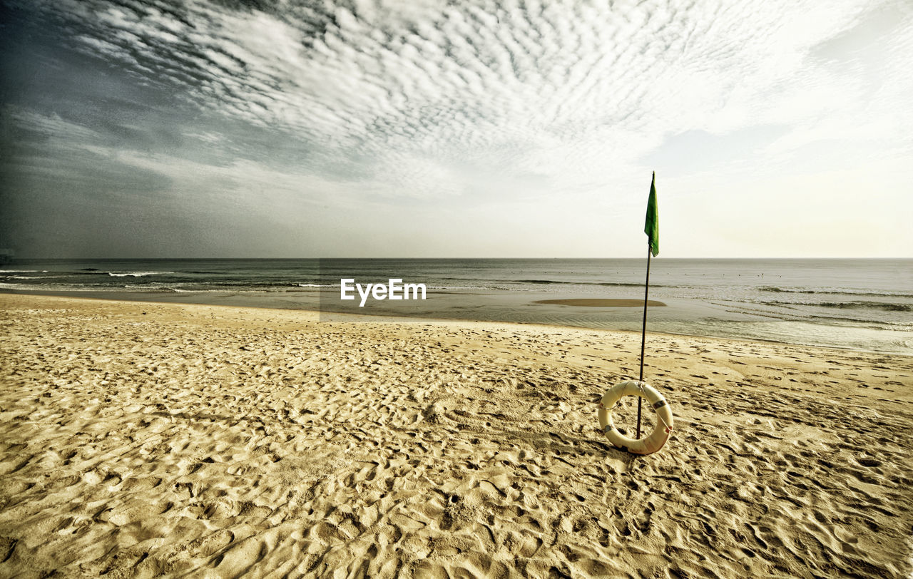 SCENIC VIEW OF CALM BEACH AGAINST CLOUDY SKY