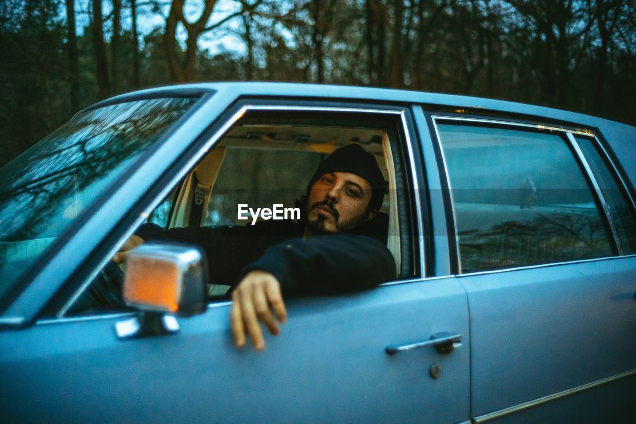 PORTRAIT OF YOUNG MAN SITTING IN CAR