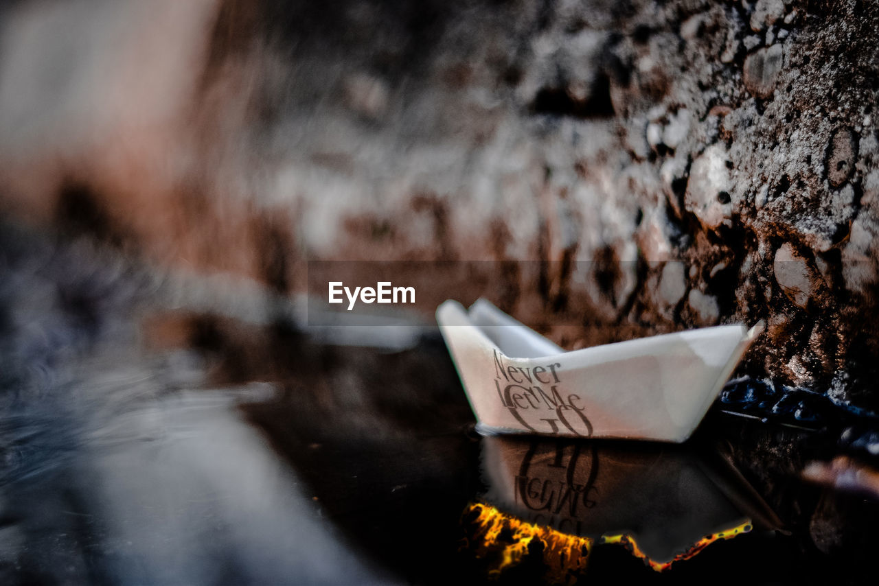 Close-up of paper boat with text in water