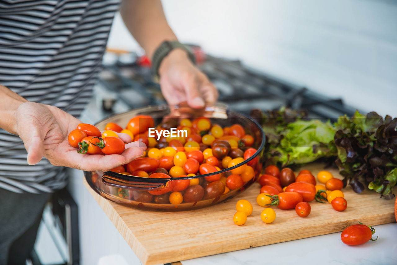 MIDSECTION OF MAN PREPARING FOOD ON CUTTING BOARD