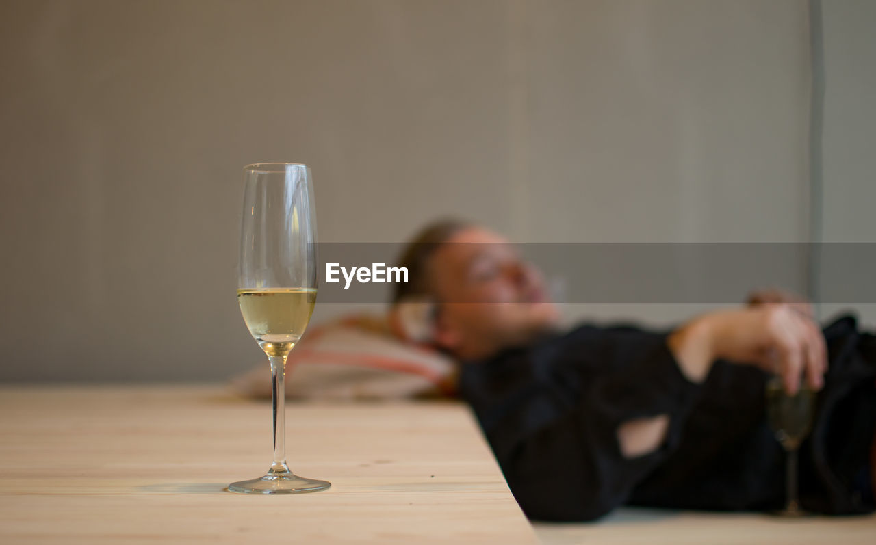 Champagne flute on table with man sleeping at home