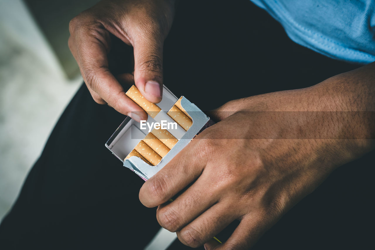 Close up man hand holding peel it off cigarette pack prepare smoking a cigarette. packing line up.