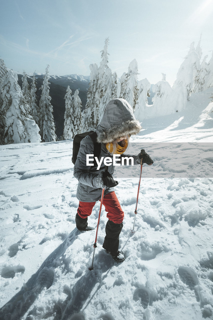 Full length of woman hiking on snowcapped mountain against sky