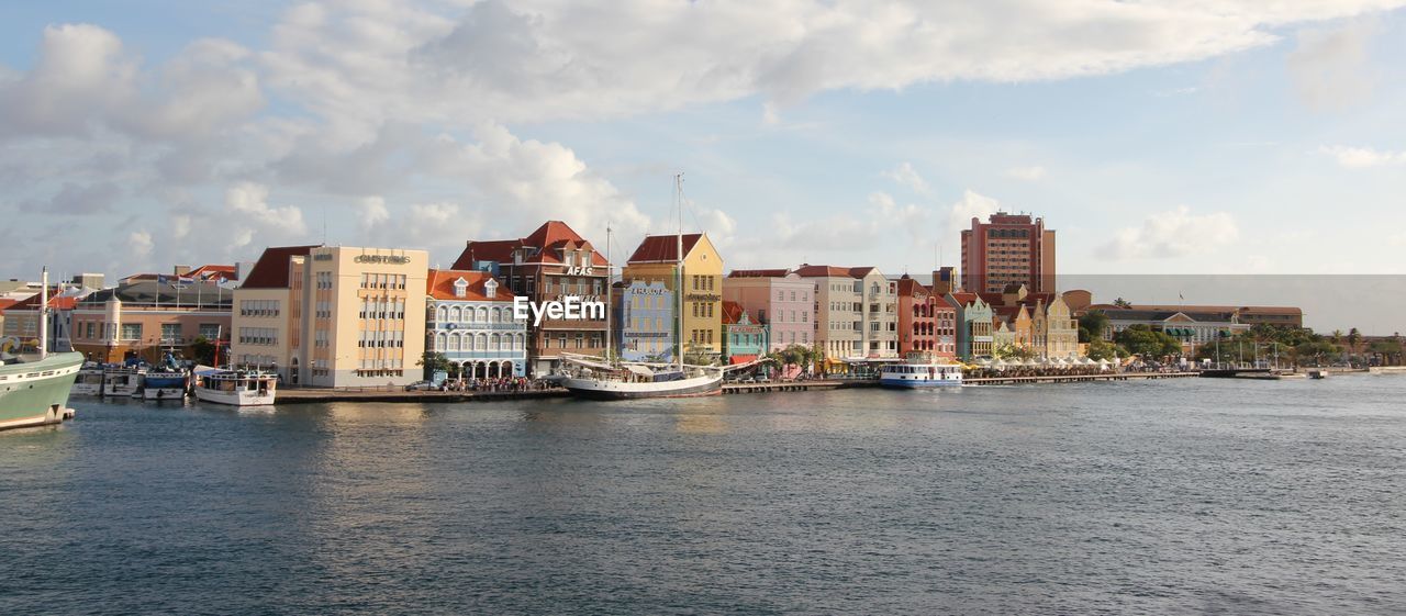 Buildings by river against sky in city