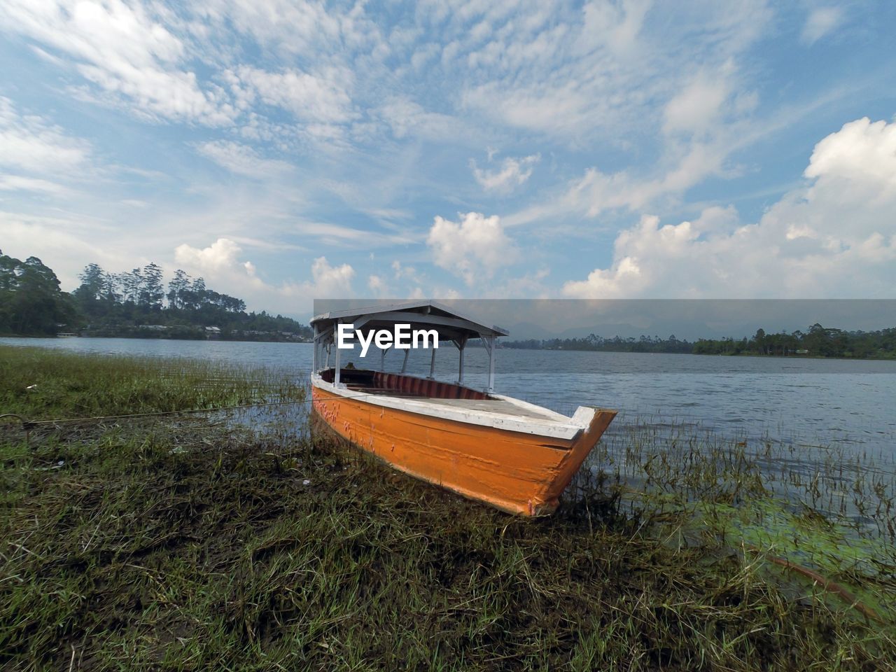 Boat moored on lake against sky