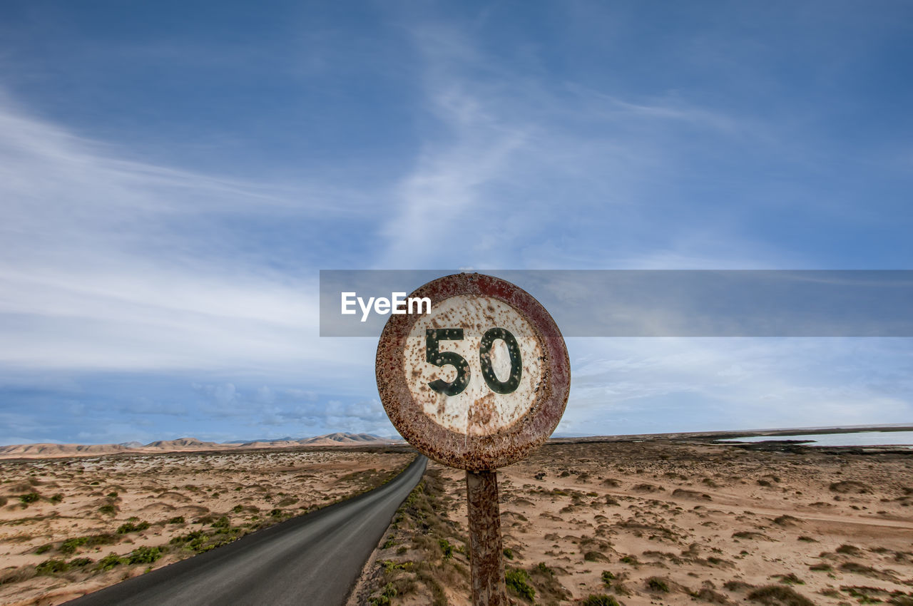 Rusty speed restriction sign on an empty road in the midle of nowhere, 50.