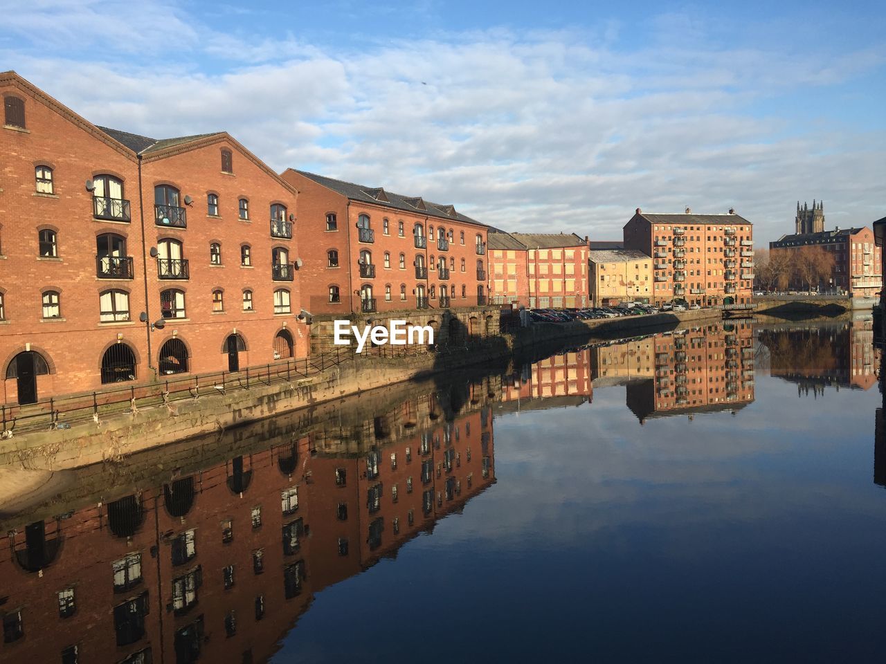 Canal by old buildings against sky