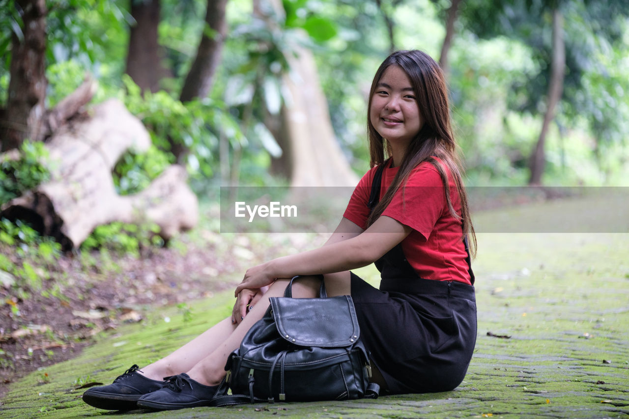 Full length of smiling young woman at park