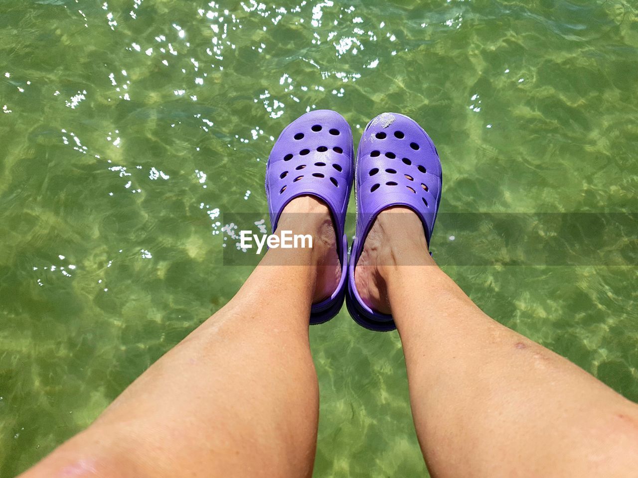 Low section of person sitting over lake