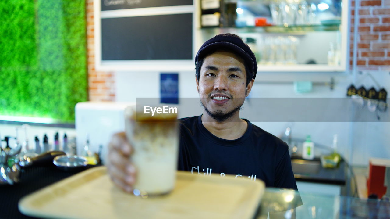 Smiling man serving drinks at cafe