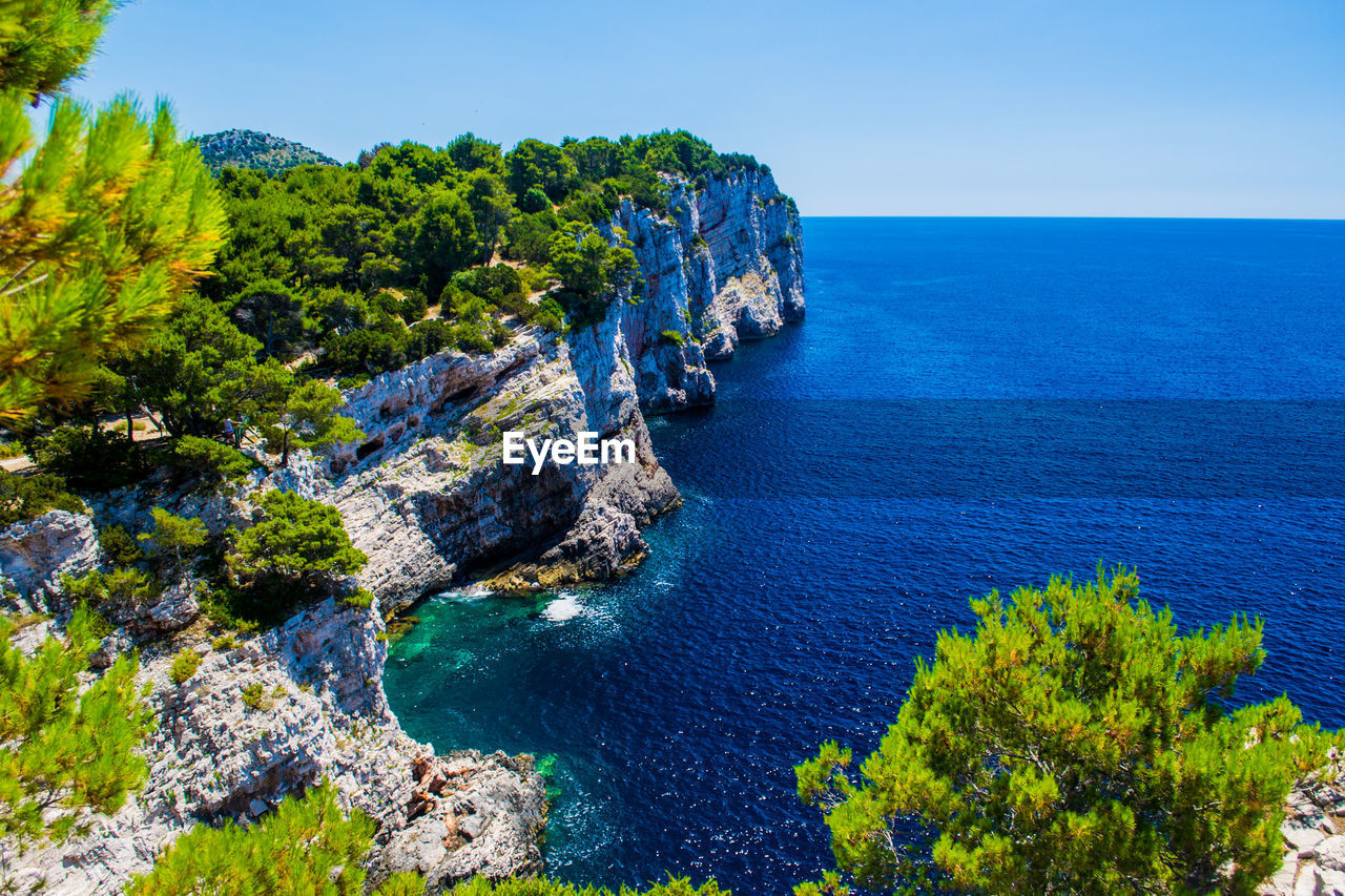 SCENIC VIEW OF SEA AND TREES AGAINST CLEAR BLUE SKY