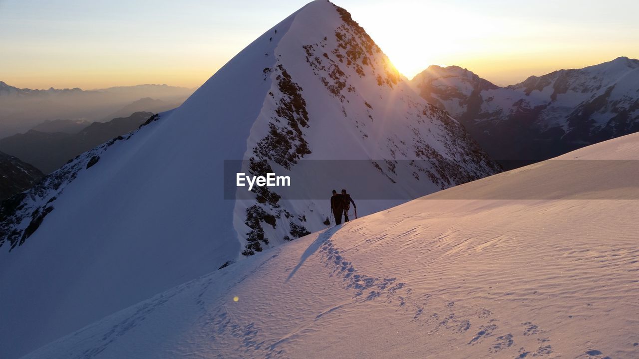 Couple on snowcapped mountain during sunrise