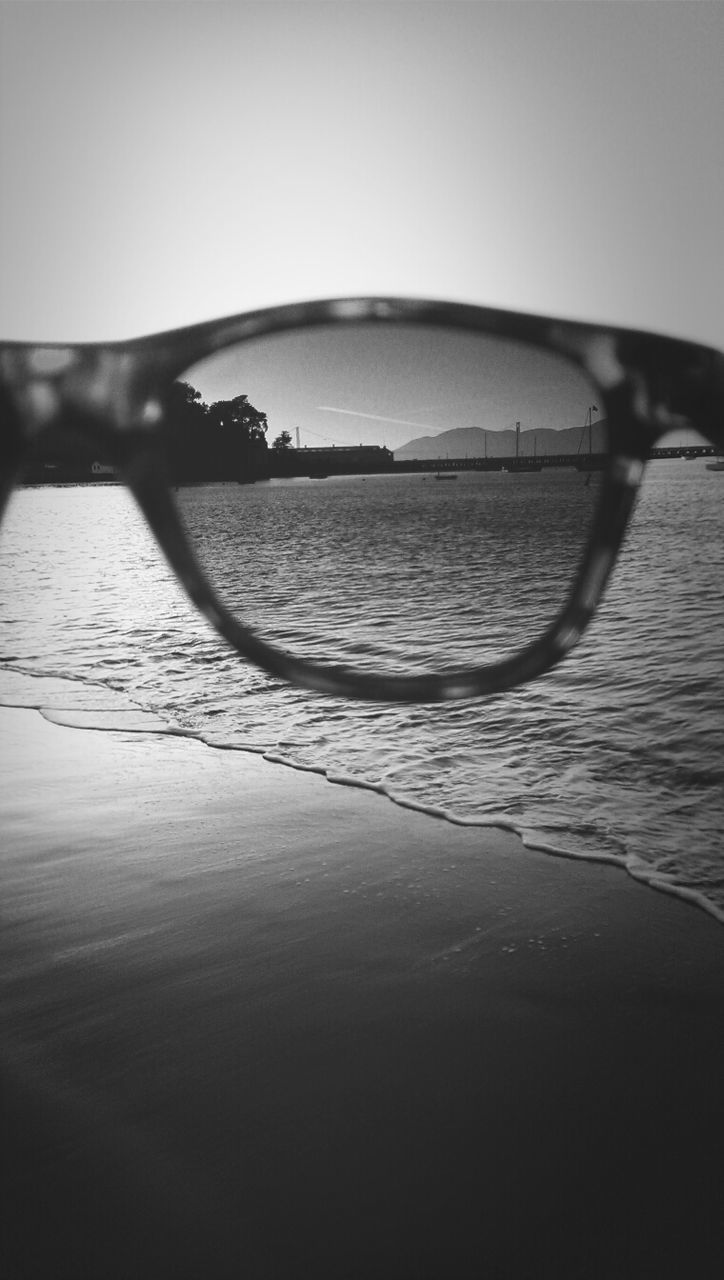 Close-up of sunglasses at calm beach against clear sky