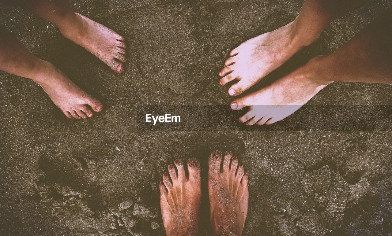 Low section of people standing on sand at beach